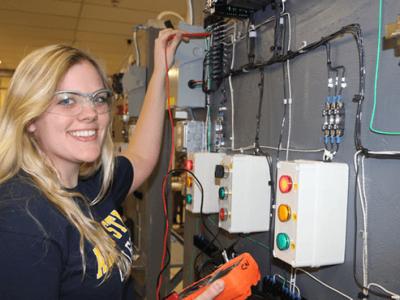 Claire Wragg holding a tool near some wires on the wall