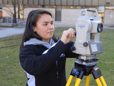 female student with survey equipment outside