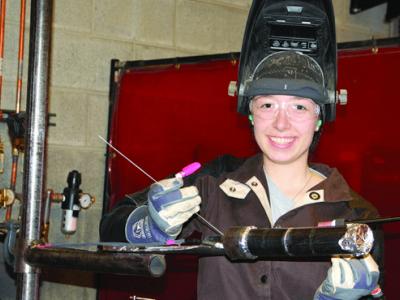 Deborah Huppman holding some welding equipment wearing a helmet