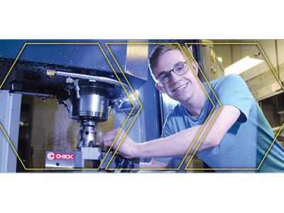 Student leaning into CNC Machine with safety glasses