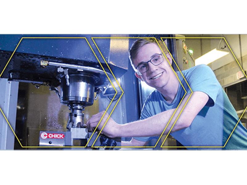 Student leaning into CNC Machine with safety glasses