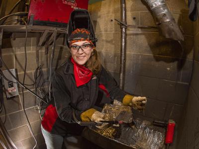 Emily Slayton wearing a welding hat and protective gear