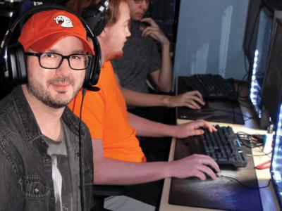 Eric Doty sitting in front of computer with headphones on wearing red hat