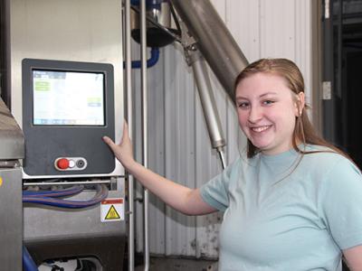 Katelyn Miller works on the robotic milking system at the barn