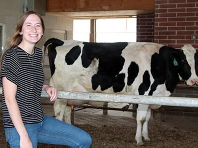Madeline Keyes stands in front of a cow at the farm