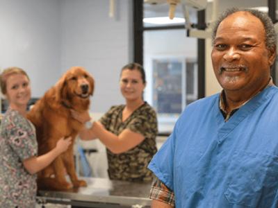 Dr. Mel Chambliss with 2 students and a dog in a lab