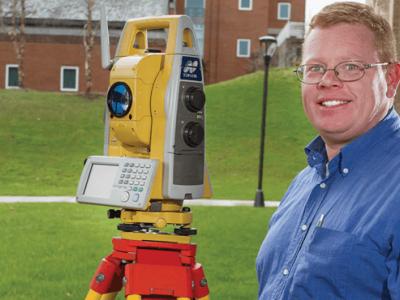 Roger O’Toole next to surveying equipment