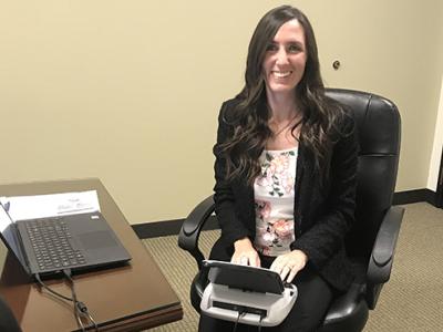 Tara sitting in front of her court reporting equipment