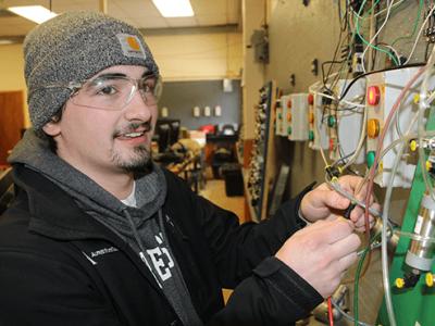 Eric holding on to some electrical wires on a board
