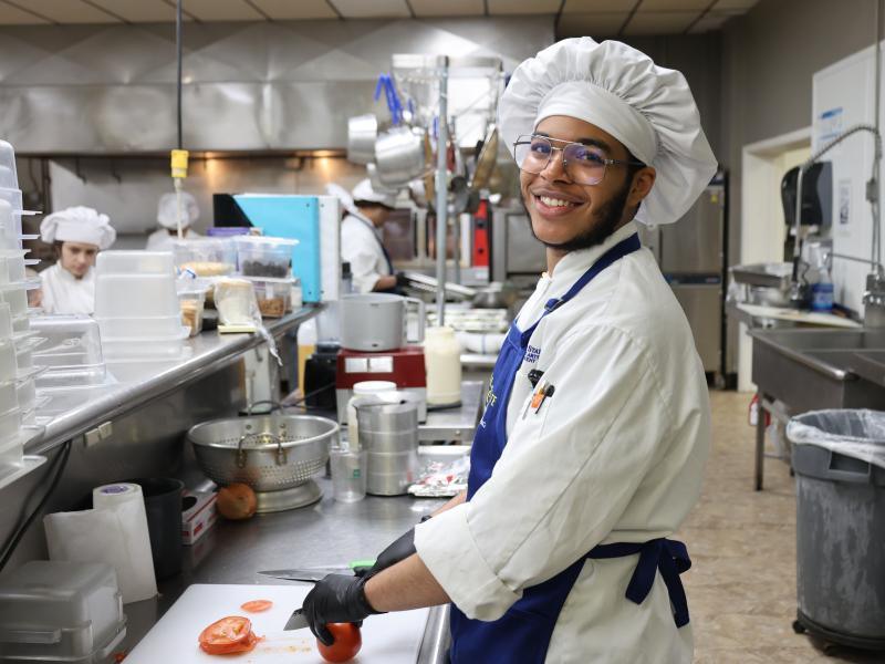students cuts a vegetable in the kitchen