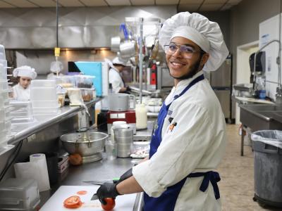 students cuts a vegetable in the kitchen