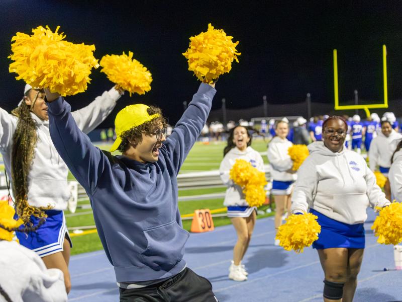 student joins the cheerleaders to keep the crowd excited during Homecoming