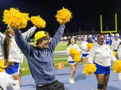 student joins the cheerleaders to keep the crowd excited during Homecoming