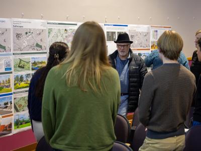 Architecture students speak with a community member at a presentation.