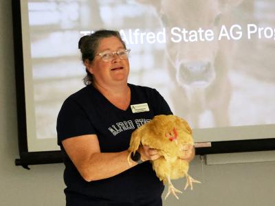 professor holds a chicken while speaking about careers in agriculture