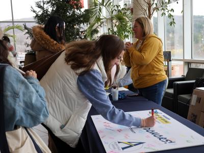 student signs a thank you card