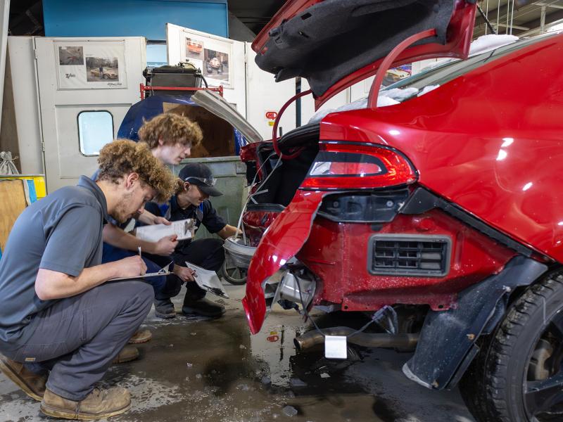 students asses the damage of a car