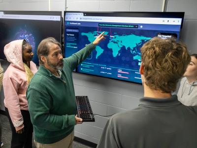 faculty works with students in a cyber security lab