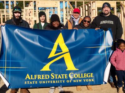 Students stand with a family that they help build a home for