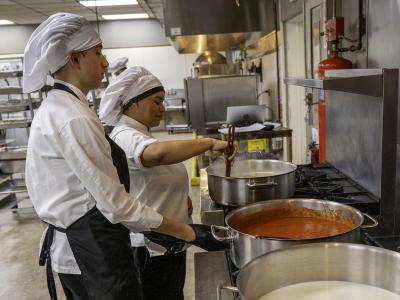 students work on sauce in the kitchen