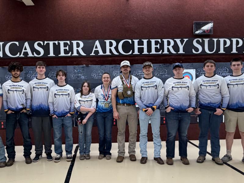 Archery team in front of a sign at Indoor Nationals