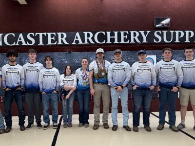 Archery team in front of a sign at Indoor Nationals