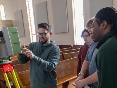 Professor works with students showing them how to use a scanner