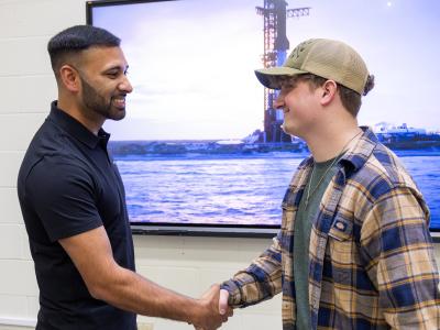 Khobir Uddin shakes hands with a current student