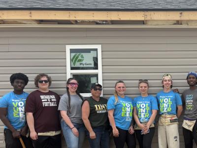 students stand in front of a house they worked on