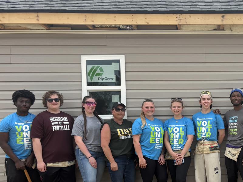 students stand in front of a house they worked on