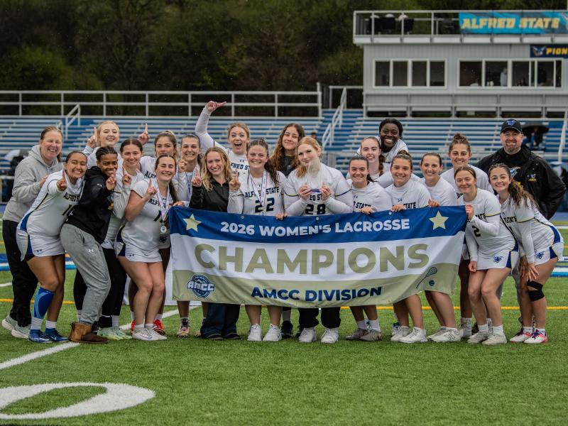 Alfred State women's lacrosse team with the championship banner