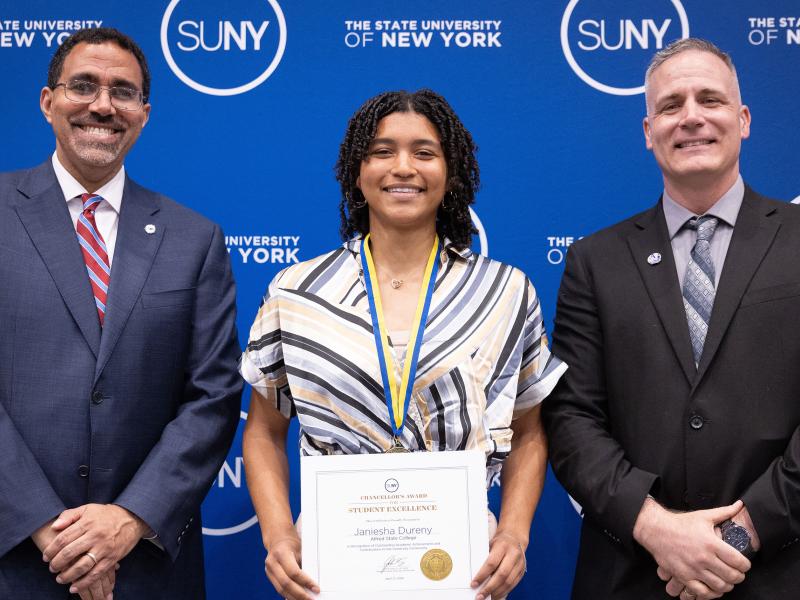 student poses with President and Chancellor after winning an award