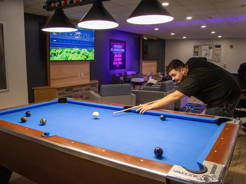 student shoots pool in the newest lounge on campus