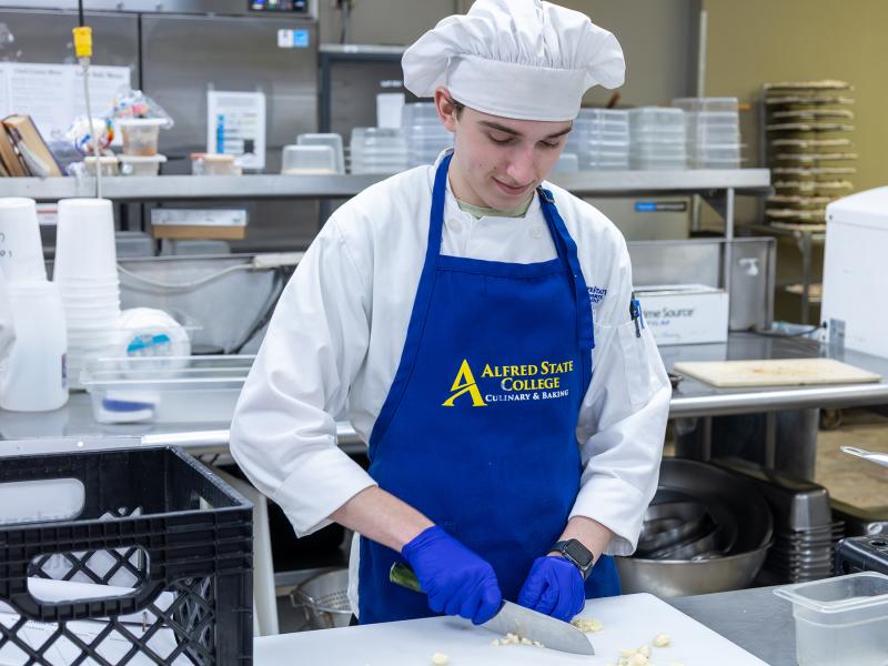 student cuts garlic in the kitchen