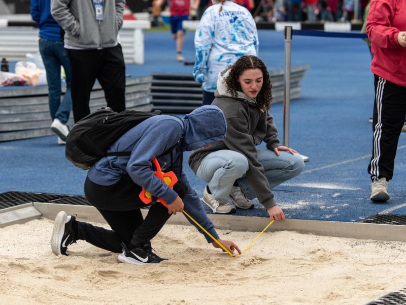Alfred State student-athletes measure a mark for an athlete participating in a jumping event at the 2026 Alfred State Track & Field Spectacular.