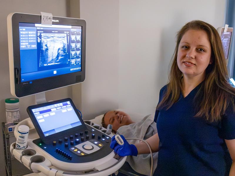 student smiles while working on a sonography machine