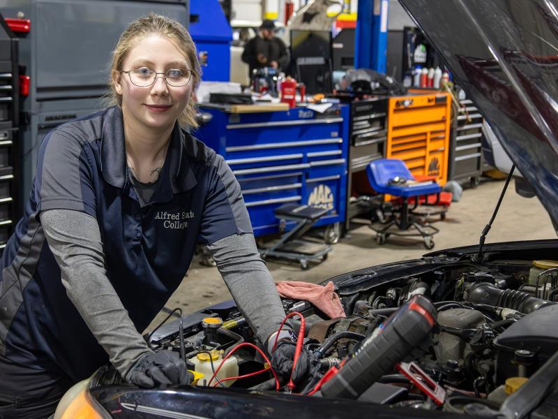 student works under the hood of a car in a shop