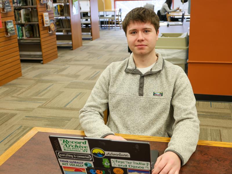 Student sits with laptop in library