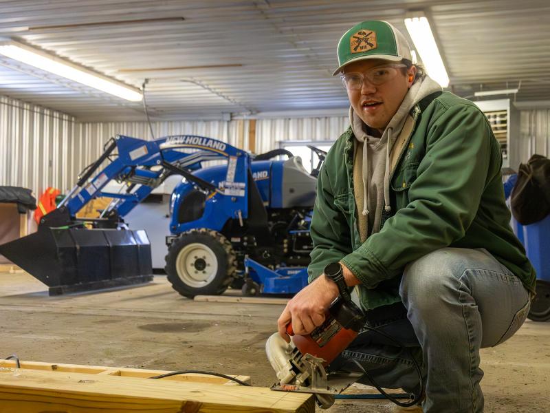 student working on a structure in a barn