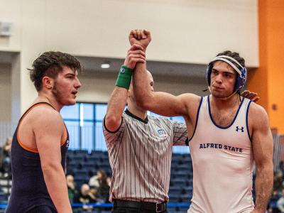 A wrestler has his arm raised in victory