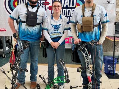 Archers stand in front of a sign at Indoor Nationals