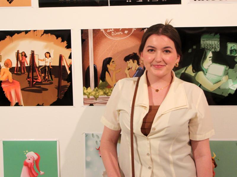 student stands in front of her artwork 
