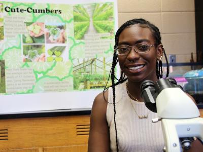 Student sitting next to a microscope