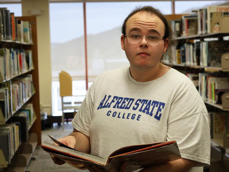 student looking at a book int he library