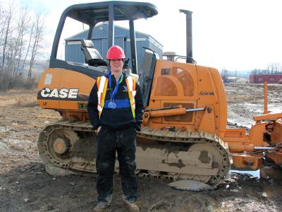 Conor Compton poses by a bulldozer with his medals from the Allegany-Empire Championships. Compton will compete at the NCAA Championships this week.