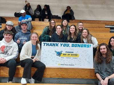 students sitting in the bleachers with a thank you banner.