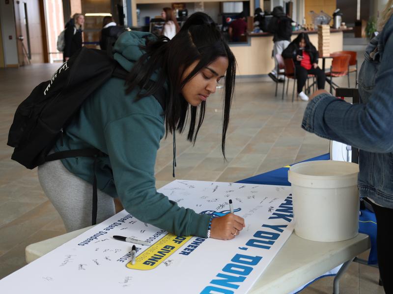 student signs a thank you card