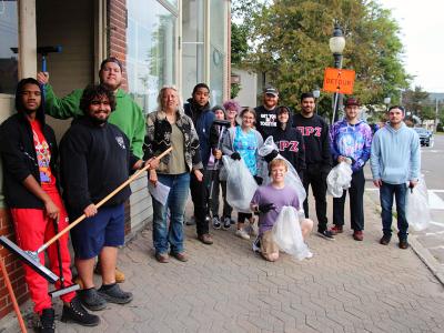 Students take a break to pose outside downtown businesses during the Day of Service. Students from Alfred State and Alfred University joined the community to spruce up areas around Main St.
