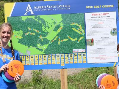 students in front of disc golf sign