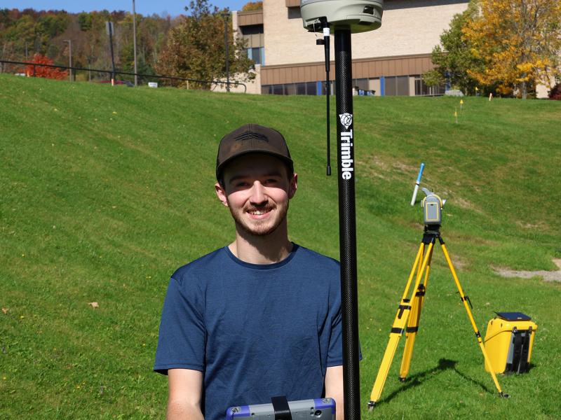 Adam Estes stands with surveying equipment